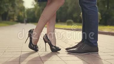 年轻夫妇站在城市里互相亲吻。 女人高兴地抬起脚趾